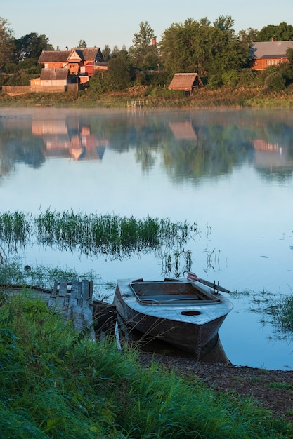 볼호프 강(Volkhov river)에 있는 러시아 마을 스타라야 라도가(staraya ladoga)의 목조 부두 옆에 있는 오래된 노 젓는 배