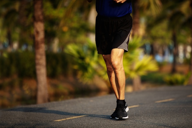 Old runner feet running on asphalt road closeup 