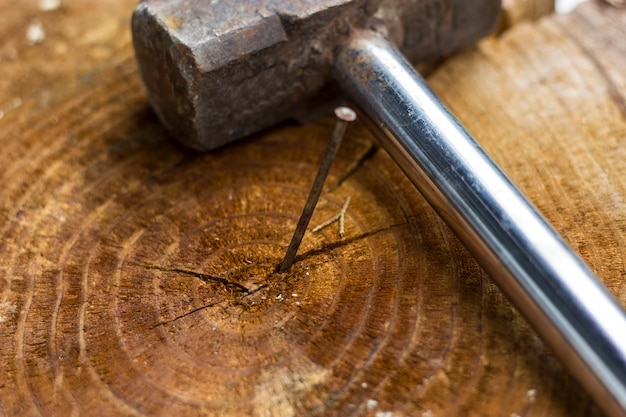 Old rust hammer and nail on wood board