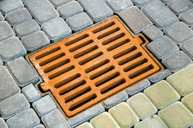 Old rusted metal gutter for rain water on the stone paved sidewalk