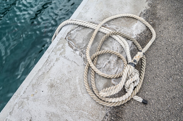 Old rusted mooring bollard with knotted nautical ropes. Los Gigantes, Tenerife