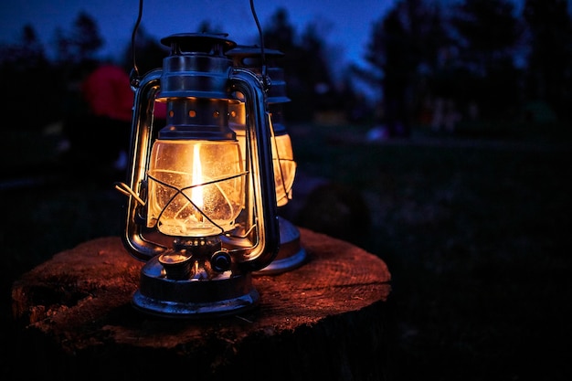 A old rustic oil lantern on a wood block at a camping site