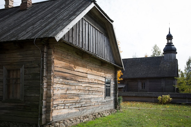An old rustic wooden hut. In the background there is a rustic wooden church. High quality photo