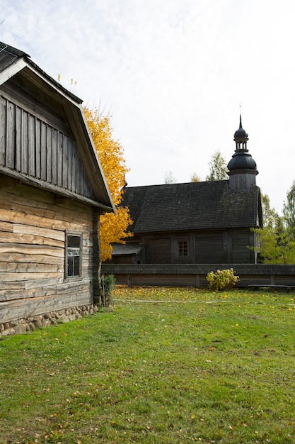An old rustic wooden hut. In the background there is a rustic wooden church. High quality photo