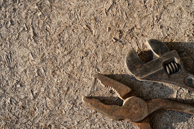 Photo old rusty adjustable wrench and pliers on wooden background