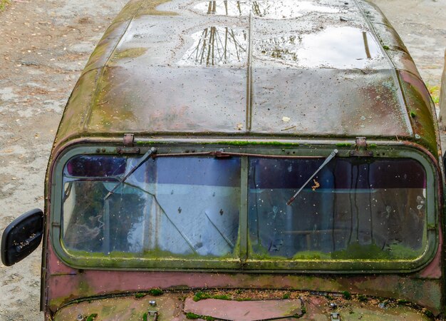 An old rusty car on the street.