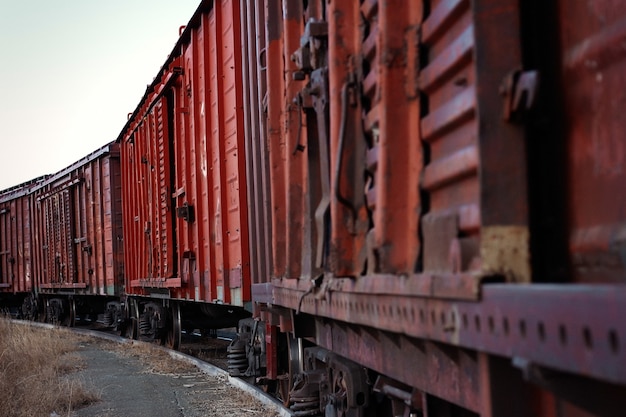 Old rusty freight train stands on rails foreground blurred sharpness from the middle of the car to the end of the train