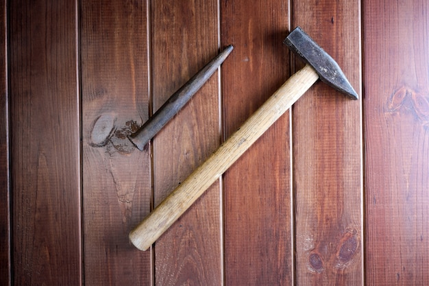 Old rusty hammer and punch on dark brown wooden background close-up