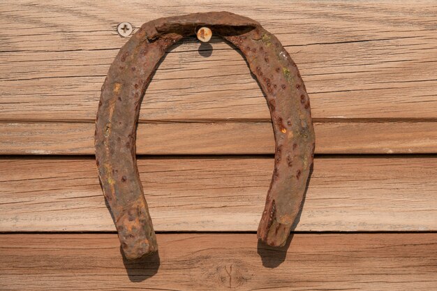 Vecchio ferro di cavallo arrugginito sul bordo di legno dell'annata