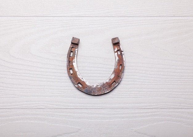 Old rusty horseshoe on wooden white surface