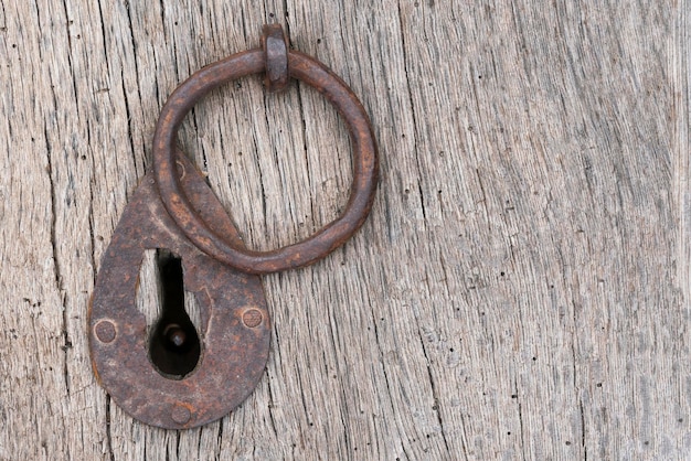 Old rusty iron ring and keyhole on a wooden background