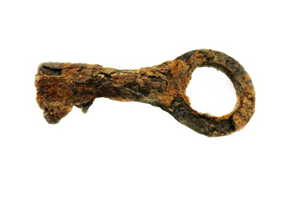 An old rusty key with uneven edges on a white background