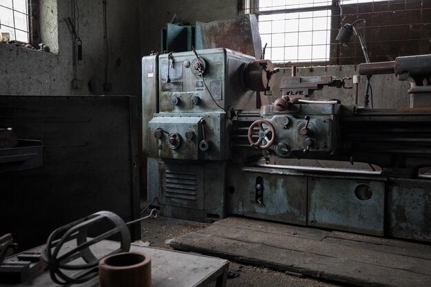 Old rusty lathe machine inside of a building