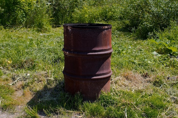 An old rusty metal barrel on the green grass