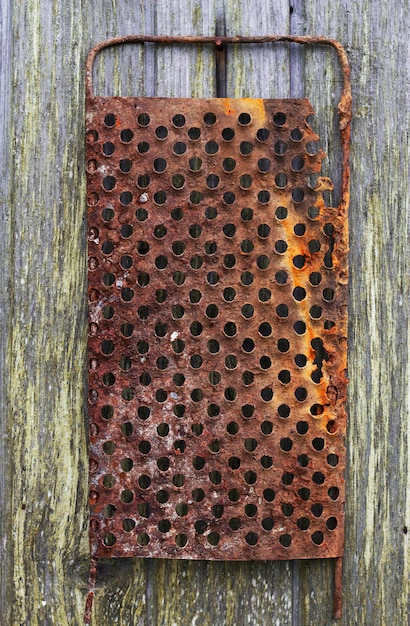 old rusty metal grater on the wooden wall as a retro background