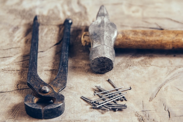 Photo old rusty pincers, nails and hammer on a wooden background.