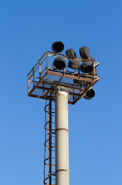 Old rusty pole of spotlights in the stadium