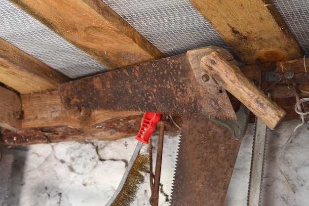 Photo an old rusty saw hangs from a nail in the garage