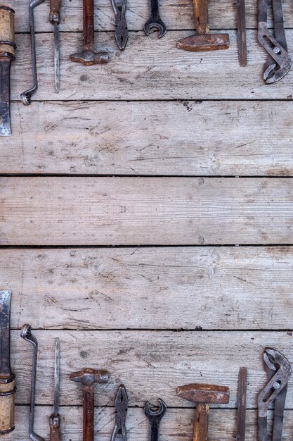 Photo old, rusty tools lying on a black wooden table. hammer, chisel, hacksaw, metal wrench.copy space