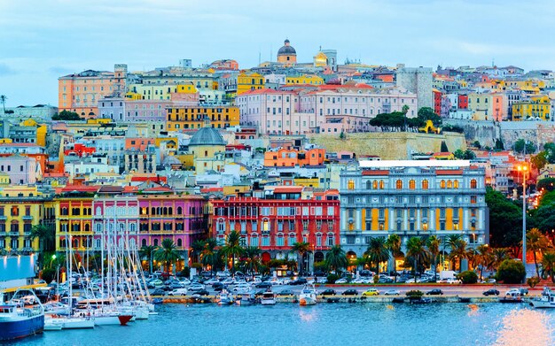 Old Sardinian Port with ships at Mediterranean Sea and city of Cagliari, South Sardinia Island in Italy in summer. Cityscape with marina and Yachts and boats in town