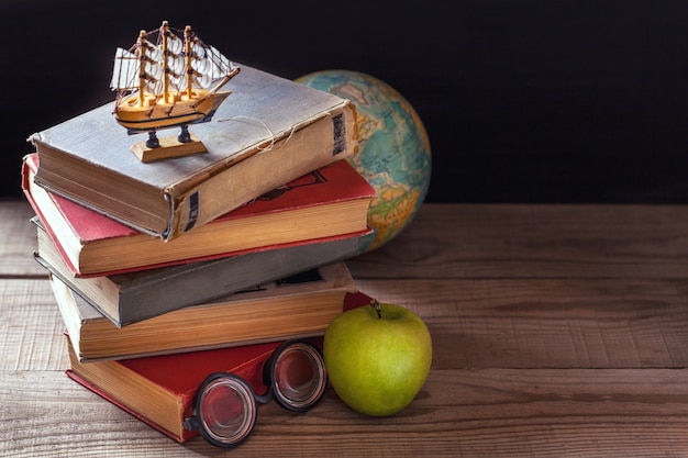 The old school books, textbooks and school supplies lie on wooden table.