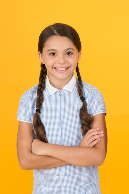 Old school fashion back to school happy beauty on yellow background happy childhood hair health concept girl with long hair smart girl in vintage dress little girl retro uniform Knowledge day