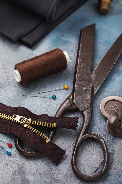 Старые ножницы, молния для одежды и другие инструменты для шитья и мелкого ремонта крупным планом