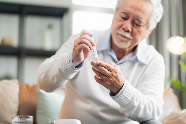 Old senior asian male hand nasal swab testing rapid tests by himself for detection of the SARS co2 virus at home isolate quarantine concept