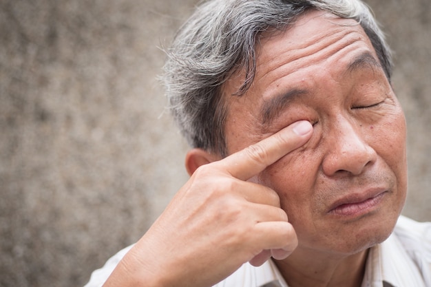 Old senior man having eye irritation
