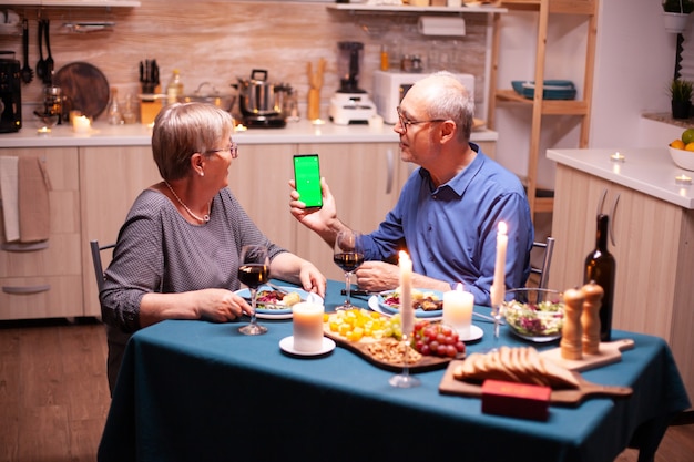 Old senior retired couple holding green screen