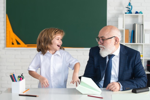 Old senior teacher and school boy pupil. Education in elementary school, kids learning concept.