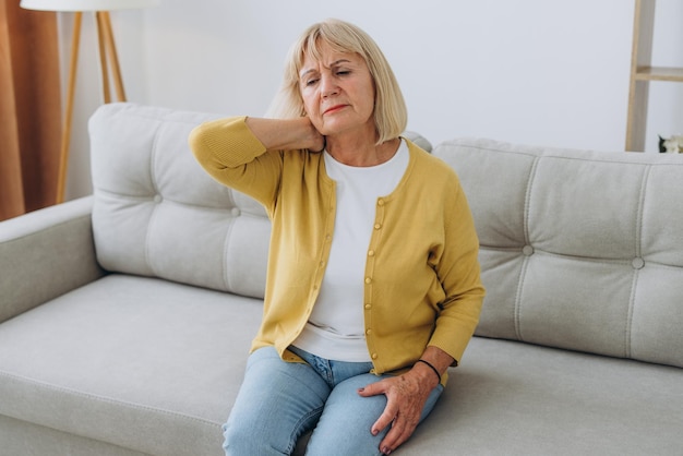 Old senior woman feeling stiff sore neck pain concept