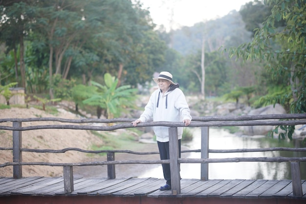 Photo old senior woman walking relaxing on bridge in park