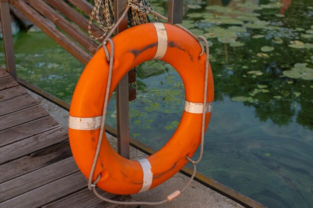 Old shabby lifebuoy on a wooden pier near the water