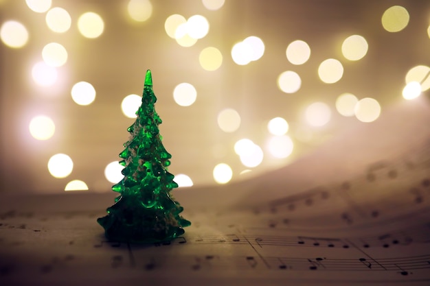 Старый лист с рождественскими нотами в качестве фона против размытых огней. Рождественская музыкальная концепция