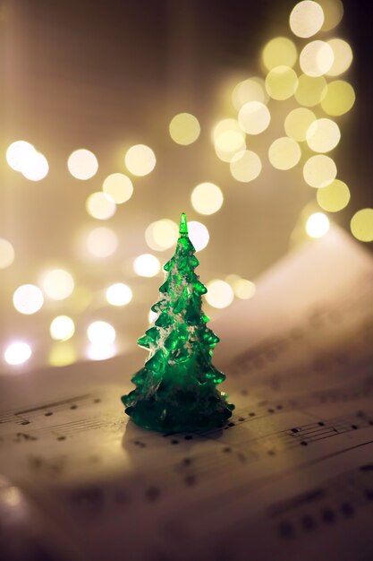 Old sheet with Christmas music notes as background against blurred lights. Christmas music concept