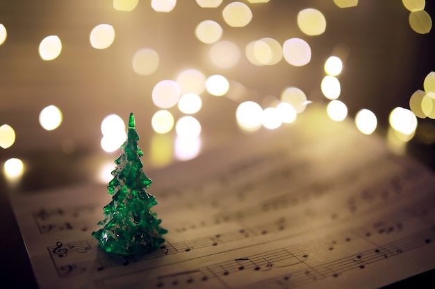 Old sheet with Christmas music notes as background against blurred lights. Christmas music concept