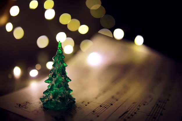 Photo old sheet with christmas music notes as background against blurred lights christmas music concept