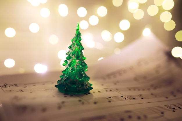 Old sheet with Christmas music notes as background against blurred lights. Christmas music concept