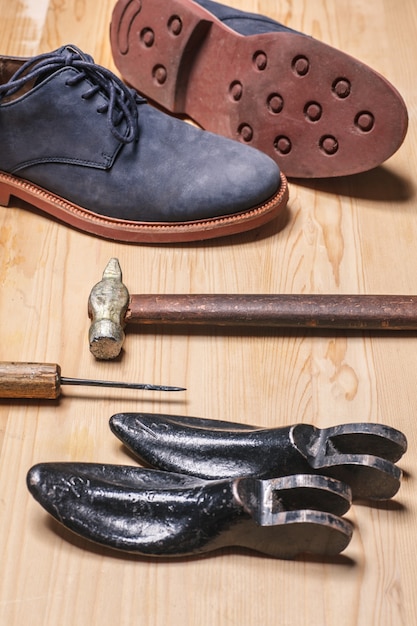 Old shoemaker tools and boots on wooden table