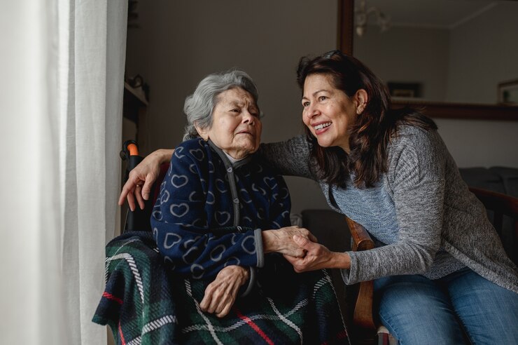 笑顔の娘の隣に車椅子の老人病人。サードエイジ、在宅ケアの概念。