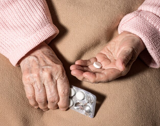 Old sick woman with pills at home