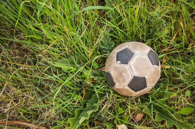 Old Soccer ball on the green grass with copy space, top view