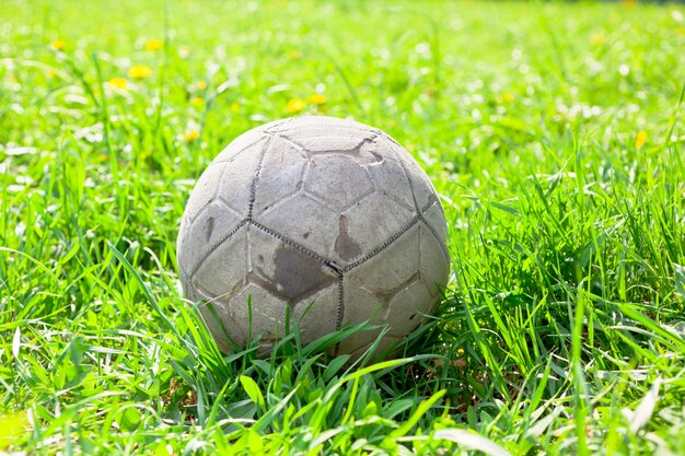 Old soccer ball on the green grass