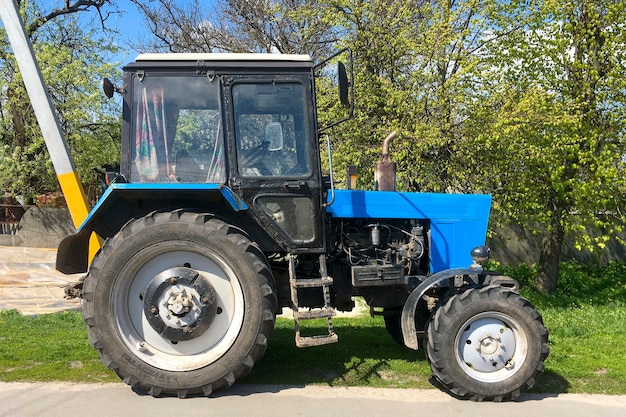 Old Soviet powerful wheeled  tractor Belarus 821 stands on side of road in village