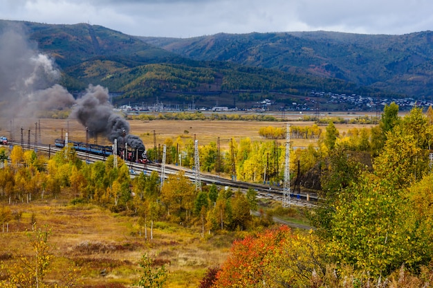 Old steam locomotive in the Circum-Baikal Railway with smoke in autumn