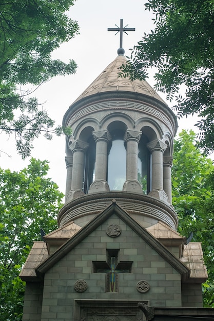 Foto una vecchia cattedrale di pietra tra un gran numero di alberi verdi.