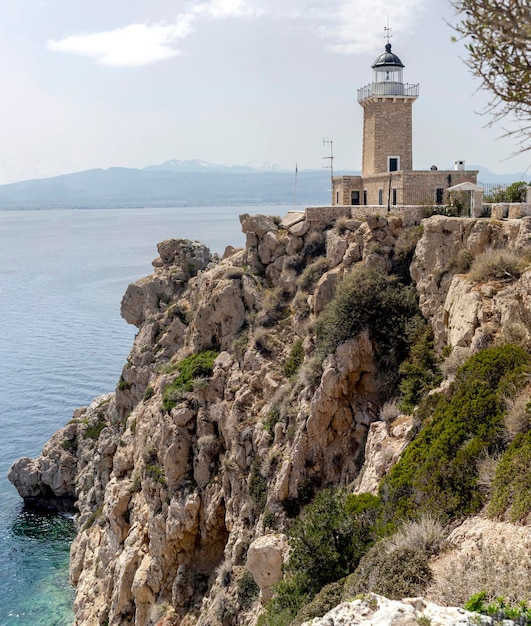 Old stone lighthouse against the backdrop of the sea and mountains