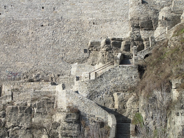 An old stone staircase near a large stone wall