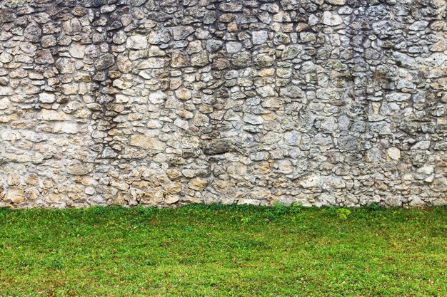 Old stone wall background with green grass